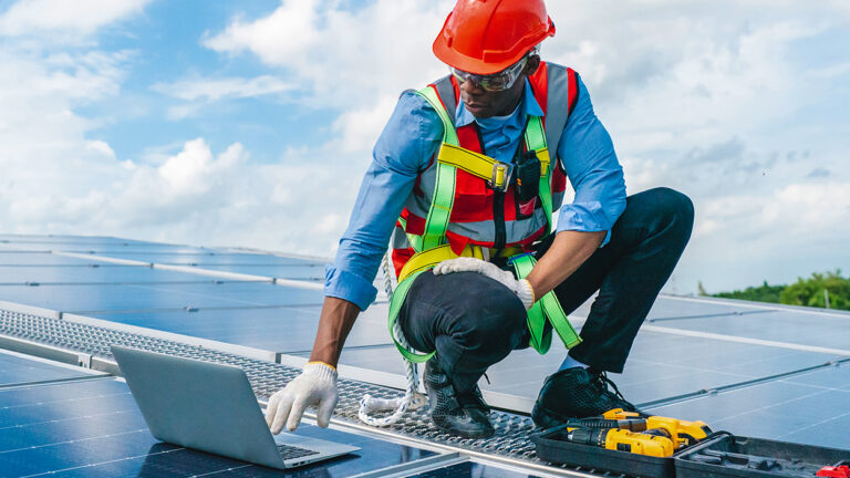 Roof Enginer maintaining solar cell panels on factory building rooftop in California